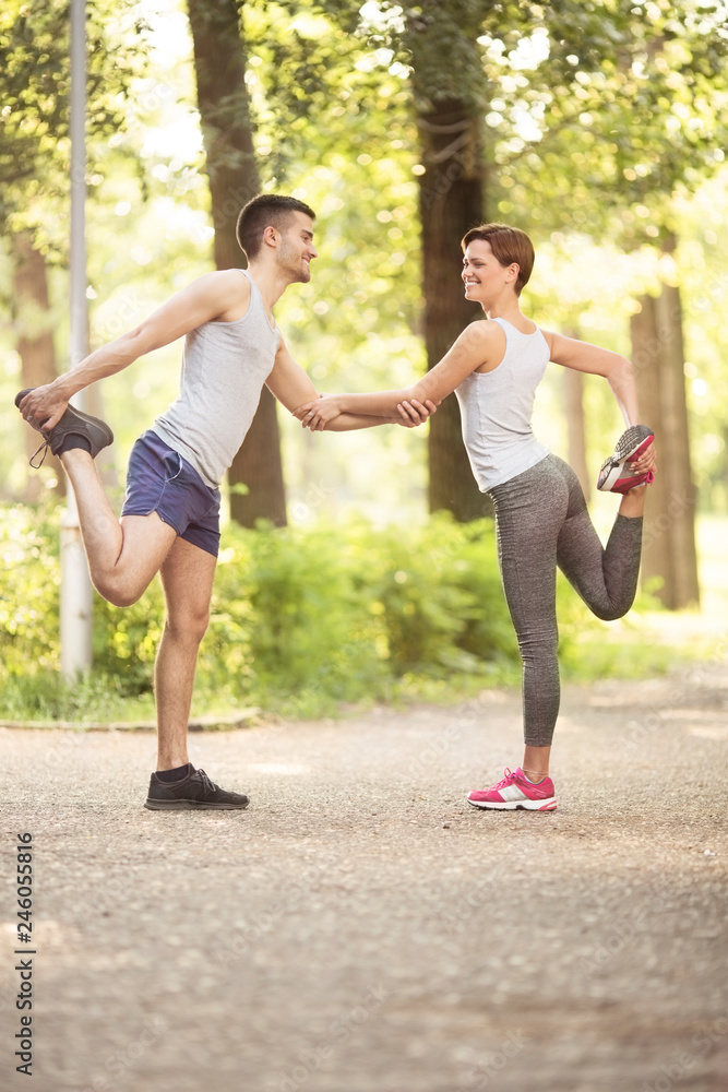 Young happy couple stretching and dating in park Young happy couple stretching and dating in park