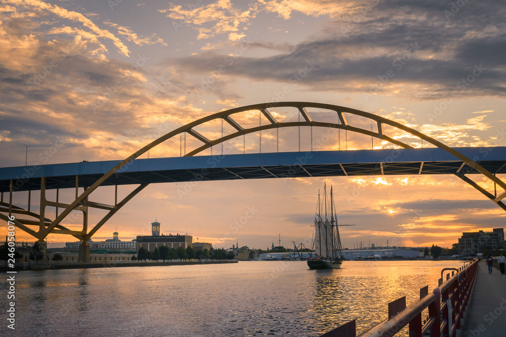 Naklejka premium Sailboat going under Hoan Bridge in Milwaukee, Wisconsin at Sunset