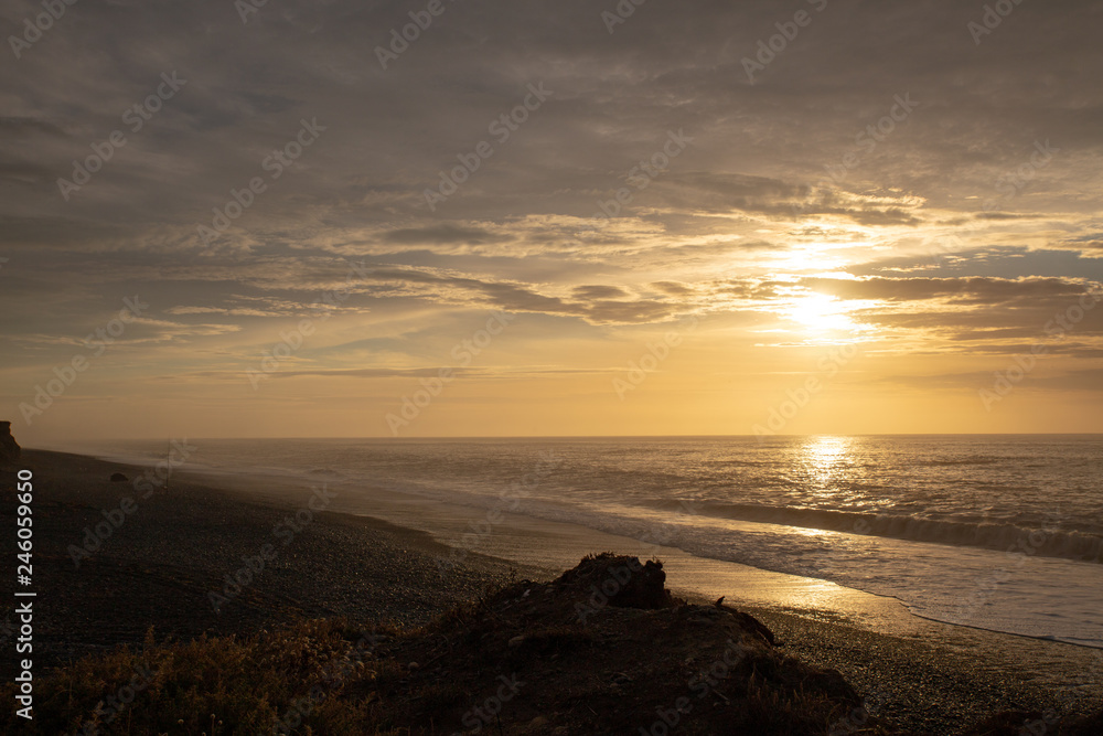 The sun rises over the ocean and disappears into the cloudy sky at Dorie, Canterbury, New Zealand