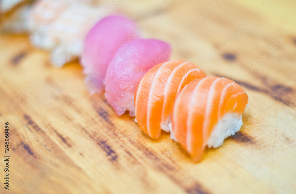 Closeup of chef hands preparing japanese food. Japanese chef making sushi at restaurant. Young chef serving traditional japanese sushi served on a black stone plate. Closeup of chef hands preparing japanese food. Japanese chef making sushi at restaurant. Young chef serving traditional japanese sushi served on a black stone plate.