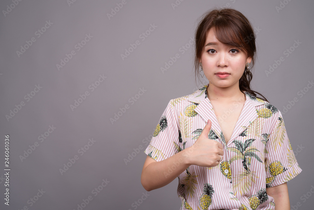 Portrait of young beautiful Asian tourist woman giving thumb up Portrait of young beautiful Asian tourist woman giving thumb up