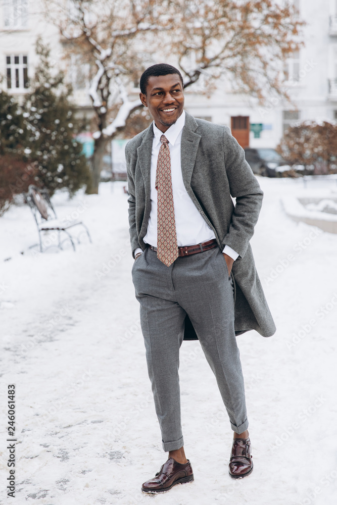 Portrait of handsome African - American businessman using smartphone in snowy winter city street, typing text message and looking at screen. Portrait of handsome African - American businessman using smartphone in snowy winter city street, typing text message and looking at screen.