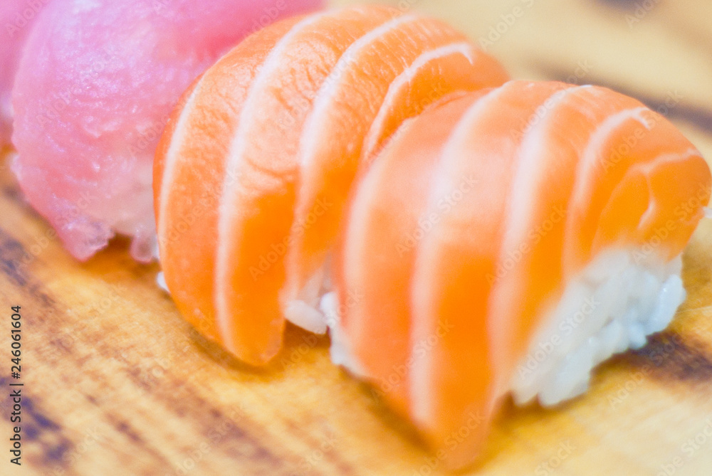 Closeup of chef hands preparing japanese food. Japanese chef making sushi at restaurant. Young chef serving traditional japanese sushi served on a black stone plate. Closeup of chef hands preparing japanese food. Japanese chef making sushi at restaurant. Young chef serving traditional japanese sushi served on a black stone plate.