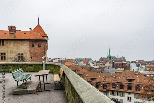 Aerial top view over old town in Lausanne, Switzerland with background of cloudy overcast sky and skyline over Geneva lake from outdoor balcony in front of Lausanne Cathedral without people. 