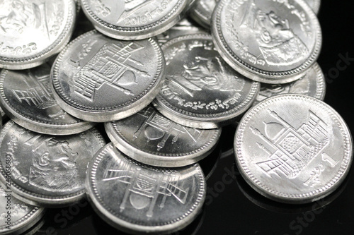 A close up image of a pile of silver Pakistani one rupee silver coins