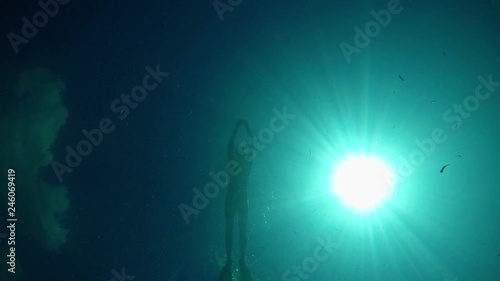 Man swimming on the surface of very clera and transparent water of Lake Ohrid in Macedonia. Shot from bottom with view of sun. photo