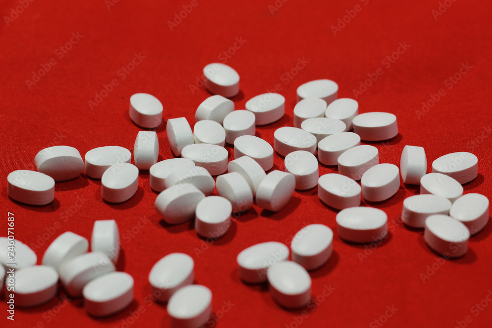 heap of white pill with red isolated background heap of white pill with red isolated background