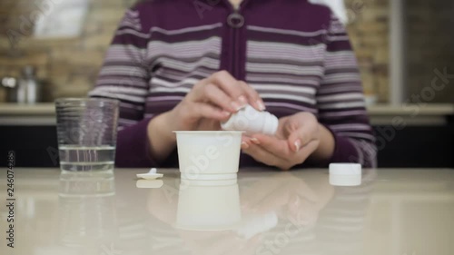 Woman drinking medicine bofore eating yoghurt. Strict medical diet. photo