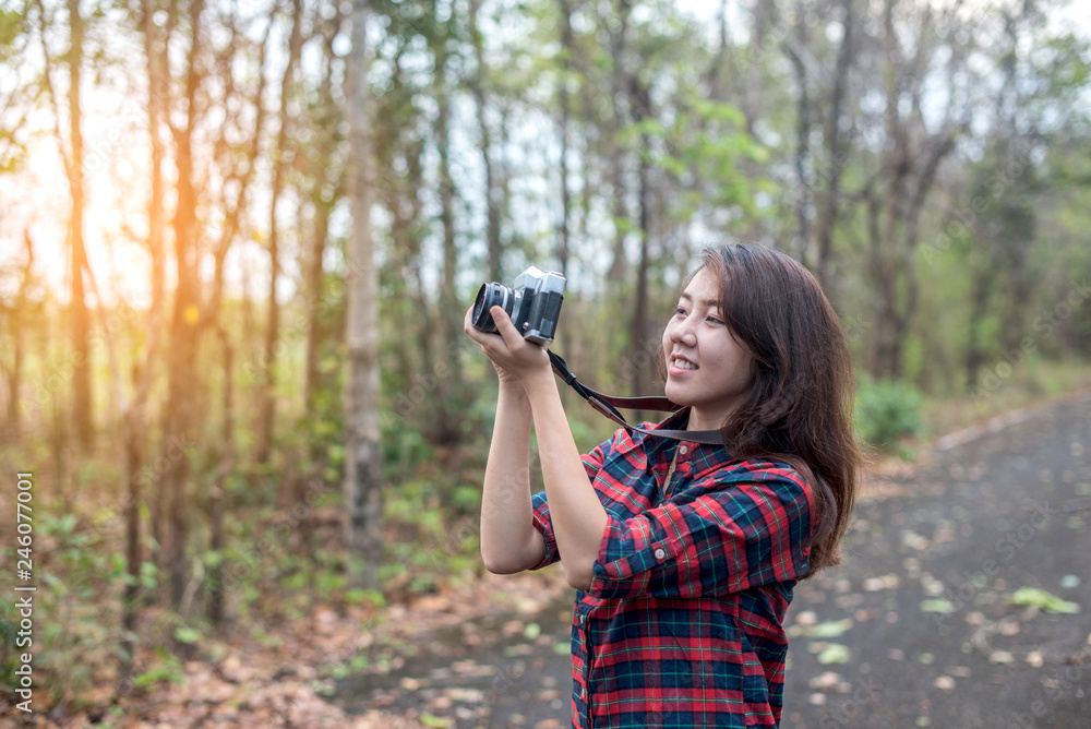 Beautiful woman with retro camera on the street in the forest alone.
