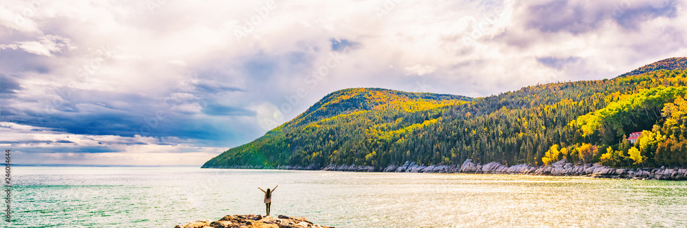 Fototapeta premium Jesień spadku natury krajobrazu gór sztandaru tło w Quebec, Kanada. Rzeka Świętego Wawrzyńca w regionie Charlevoix, Ameryka Północna. Osoba turystyczna z bronią do góry w wolności szczęśliwy z wakacji podróży.