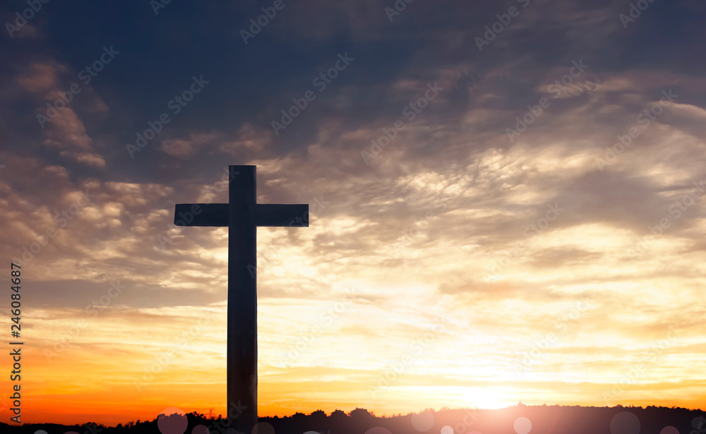 Concept of Jesus Christ: white cross on sunset sky background