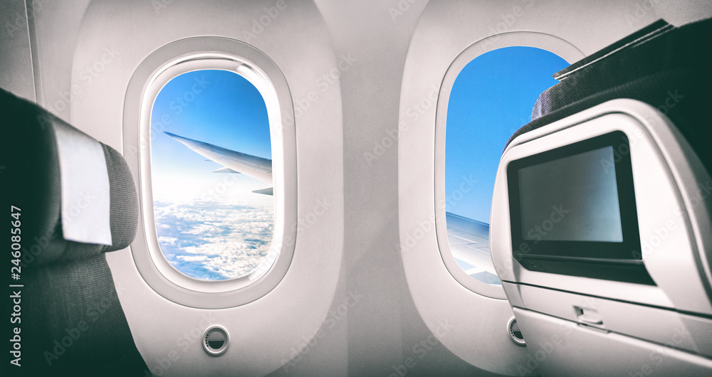 Fototapeta premium Wnętrze samolotu pasażerskiego z widokiem na latające skrzydło samolotu i ekranem filmowym.