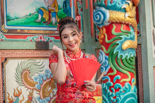 Asian girl in red dress standing in holy place on Chinese New Year. © udom