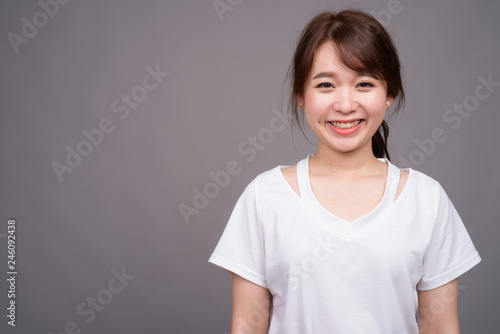 Happy Asian woman smiling against gray background