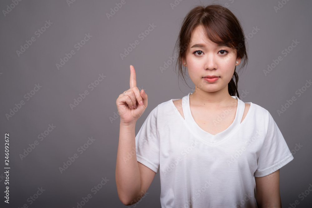 Young beautiful Asian woman against gray background Young beautiful Asian woman against gray background