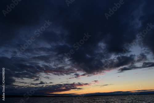 Dark clouds of the twilight sky over the water surface of the lake