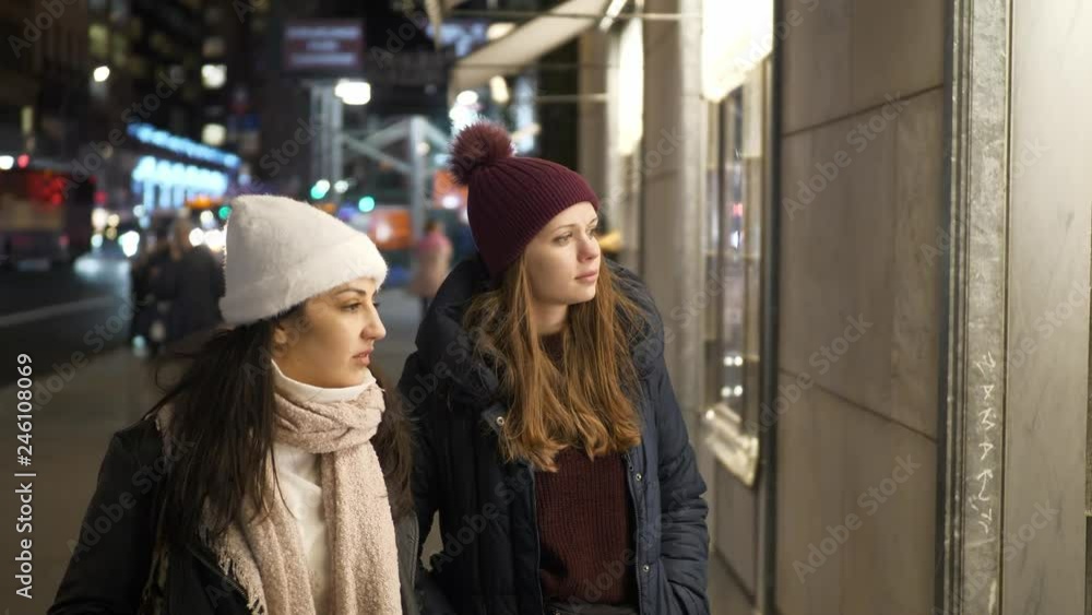 Two girls on a shopping trip in New York walk along shop windows Two girls on a shopping trip in New York walk along shop windows