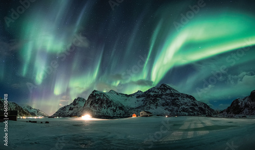 Aurora borealis or Northern lights over snow mountain on coastline