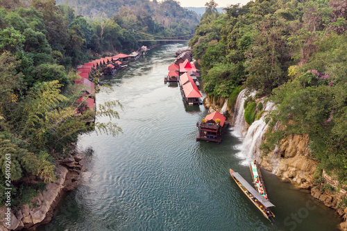 Wooden boat sailing river kwai with waterfall in tropical rainforest photo