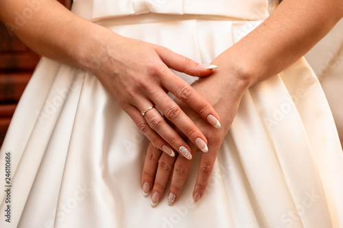 Hands of the bride on a white dress.