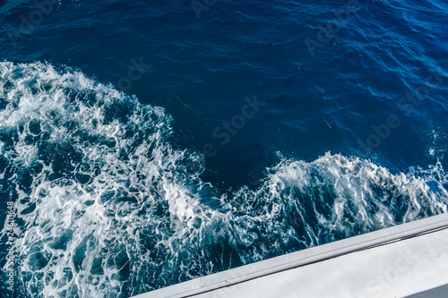 Wave trace with white foam on a water surface behind of fast moving yacht