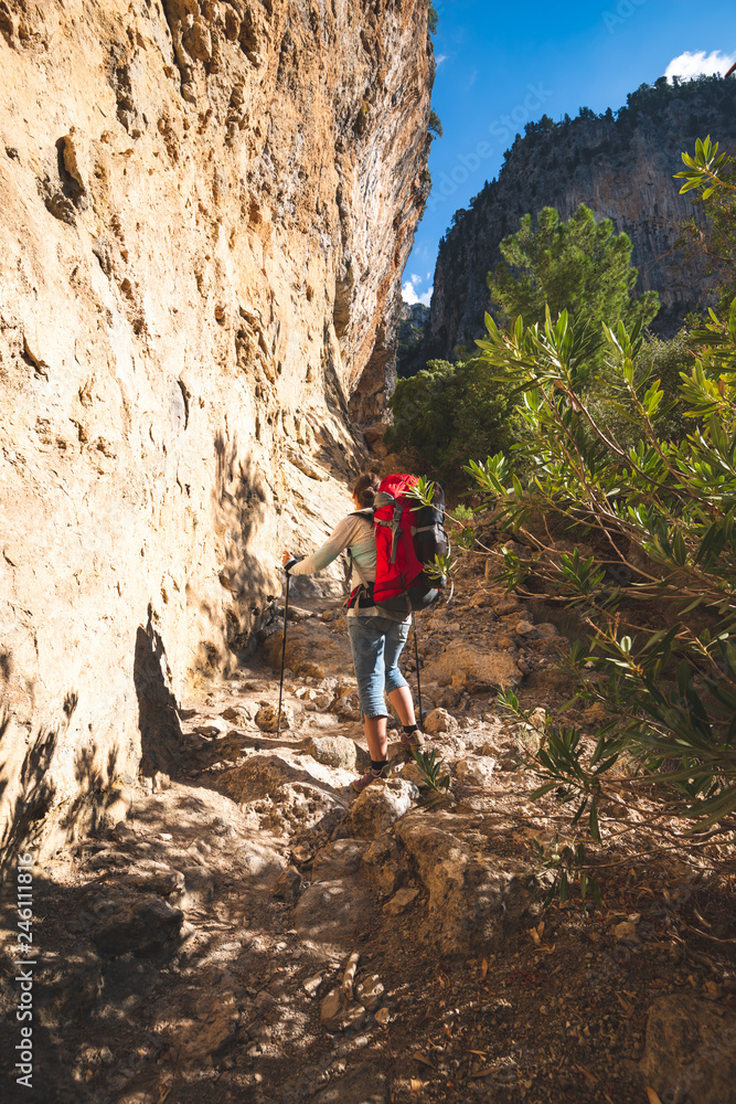 Traveler woman climbs along narrow mountain gorge