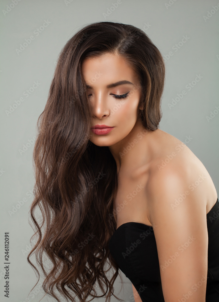 Naklejka premium Young brunette woman with long brown curly hair, natural beauty