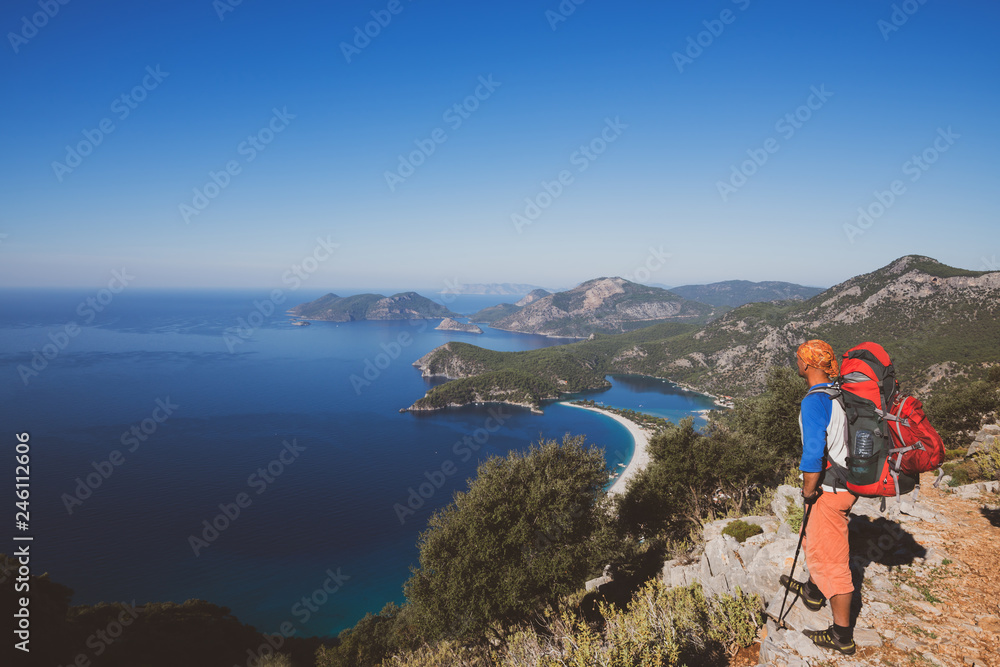 Traveler with backpack stands on the cliff