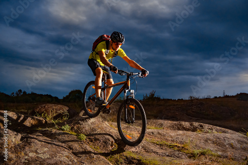 Cyclist Riding the Mountain Bike on Rocky Trail in the Evening. Extreme Sport and Enduro Biking Concept.