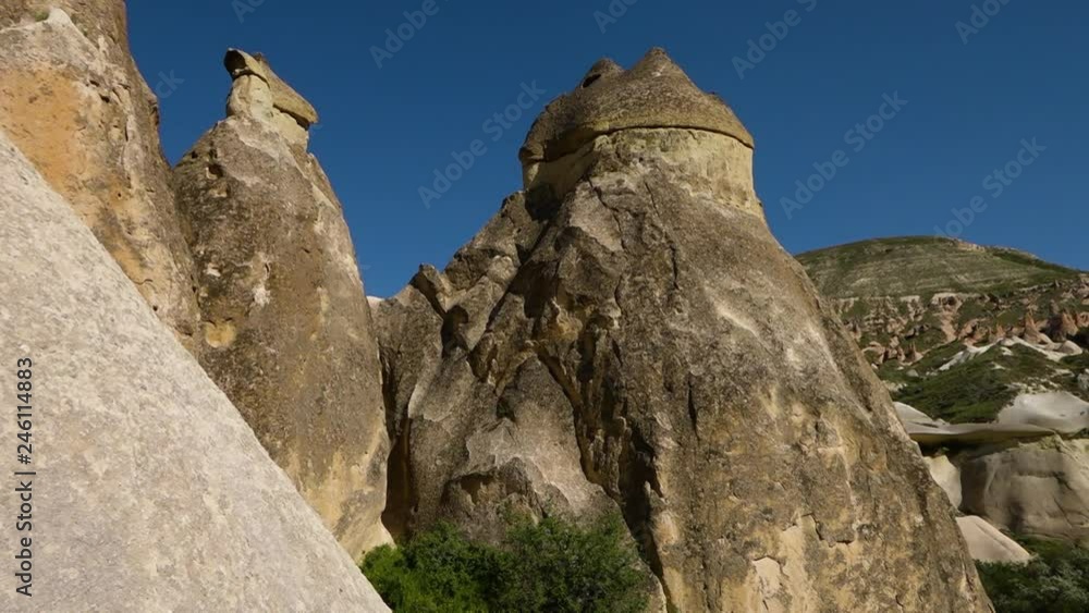 Mid shot pan left tilt up diagonally of erect vertical irregular rock formations against a blue sky Mid shot pan left tilt up diagonally of erect vertical irregular rock formations against a blue sky