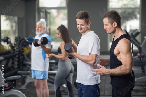 Two trainers working with clients in gym.