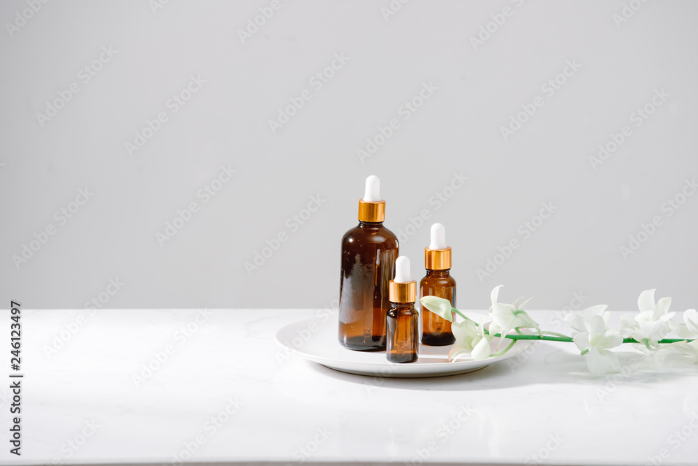 Spa setting with orchids and essential oil in a glass bottle, aromatherapy concept Spa setting with orchids and essential oil in a glass bottle, aromatherapy concept