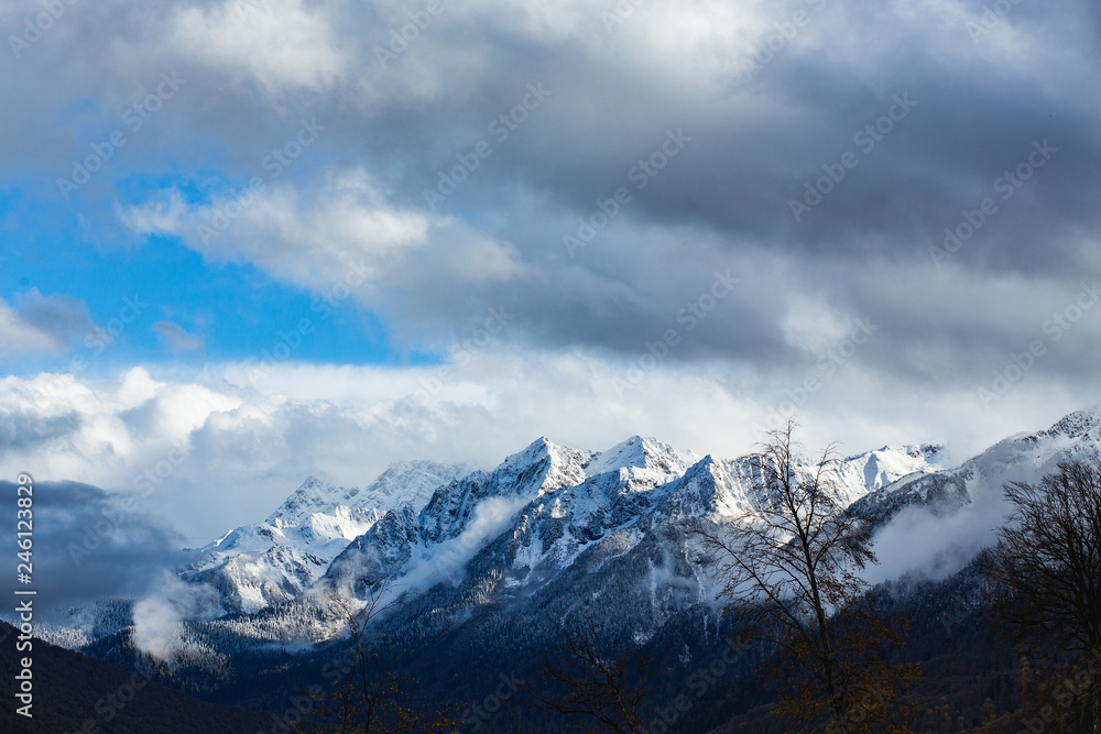 View of a beautiful mountain shrouded in blue clouds and a forest growing all over. Concept of atmospheric cyclone and anticyclone. Type of weather and environmental disaster