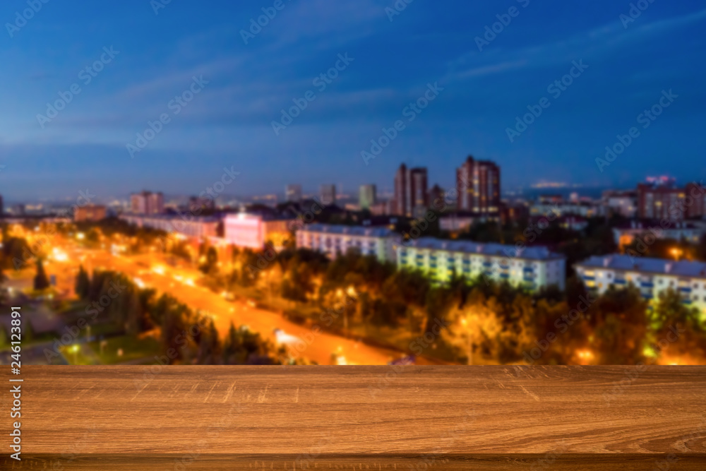 Empty wooden table with blurred background of night city. Can be used for display or montage product