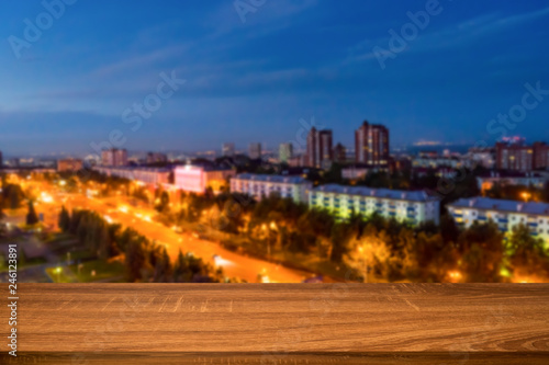 Empty wooden table with blurred background of night city. Can be used for display or montage product