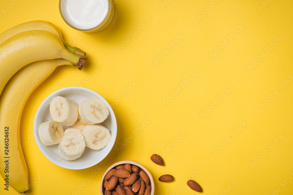Φωτογραφία Almond milk in a glass with almond nuts and bananas on a yellow background
