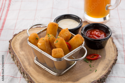 Delicious mozzarella cheese sticks breaded with ketchup and mayo in the background photo