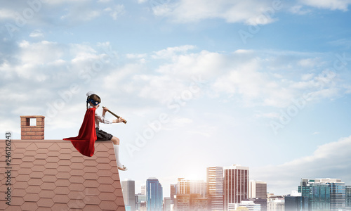 Girl power concept with cute kid guardian against cityscape background. Mixed media
