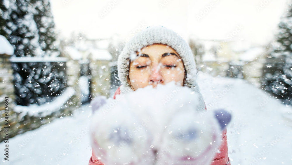 happy joyful smiling woman in warm winter clothes holding a snow in a both palms and shows it at the camera. happy joyful smiling woman in warm winter clothes holding a snow in a both palms and shows it at the camera.