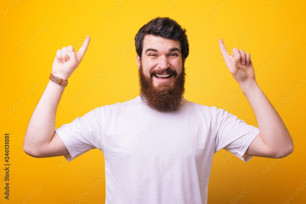 Portrait of happy man with beard pointing up at copyspace and looking at the camera Portrait of happy man with beard pointing up at copyspace and looking at the camera
