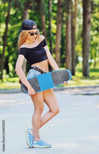 Beautiful young woman holding a skateboard