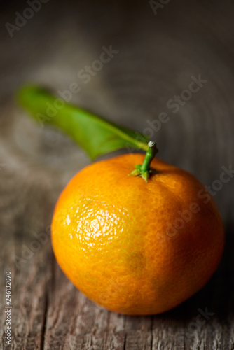 selective focus of tasty tangerine with green leaf on wooden table