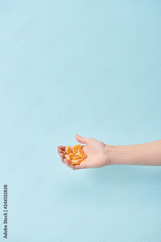 cropped view of woman holding slices of tasty peeled tangerine in hand isolated on blue cropped view of woman holding slices of tasty peeled tangerine in hand isolated on blue