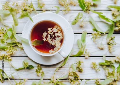 Cup of linden tea on linden blossom background. Herbal medicine.