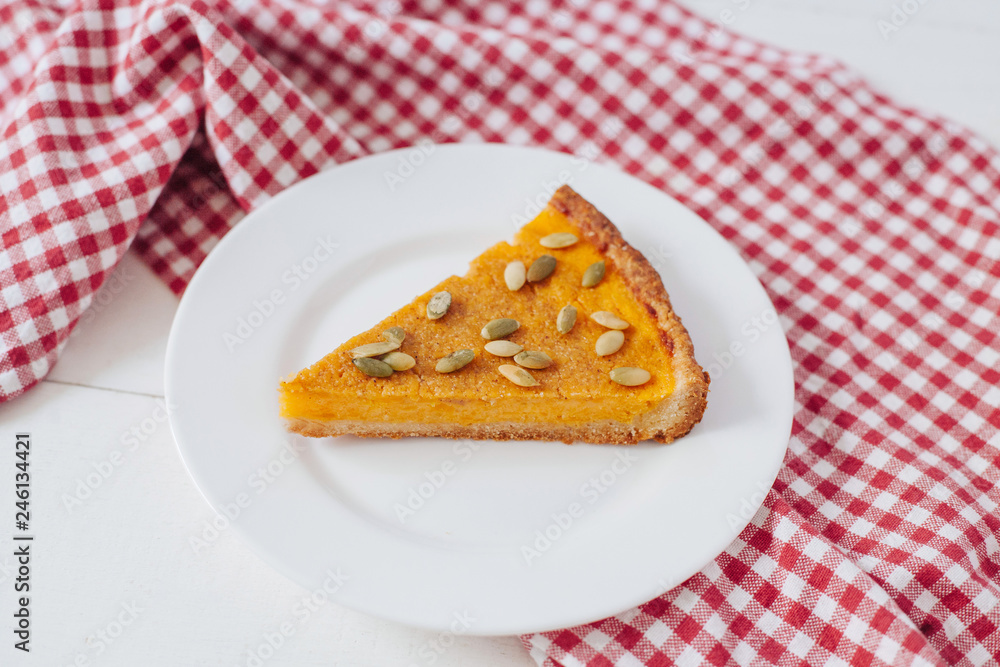 Pumkin pie with seeds on white plate with spoon and napkin