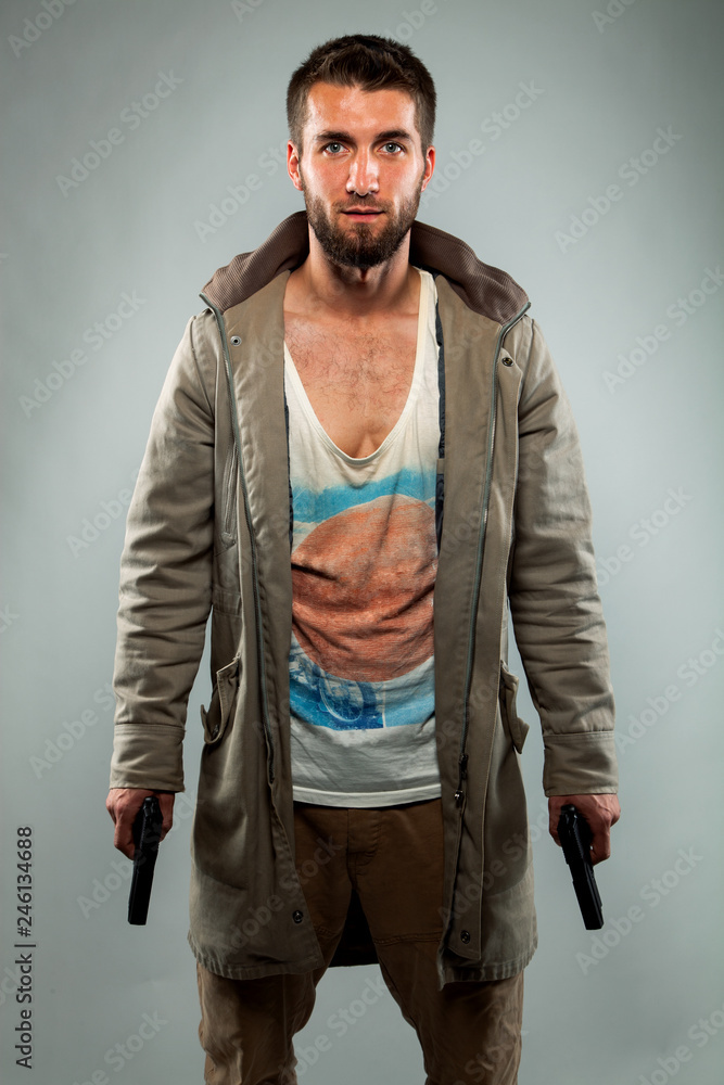 Fototapeta premium Portrait eines jungen bärtigen Mannes mit zwei Pistolen