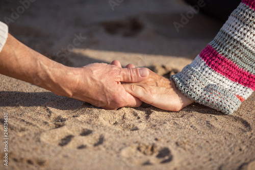 man and woman hands joined together on the sand