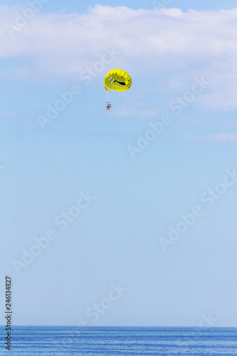 vacationers fly on a yellow parachute on a summer holiday by the sea in the resort