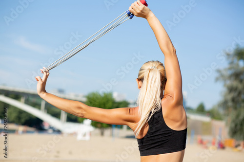 Stunning fitness woman with perfect slim body doing stretching with jump rope. Copy space © vpavlyuk