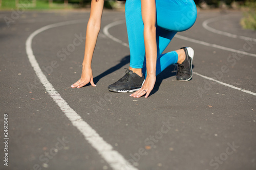 Woman runner in start position train before the race. Empty space